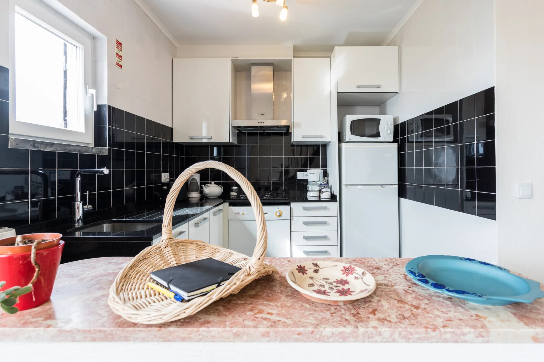 A kitchen with white cabinets, black tile backsplash, and a countertop.