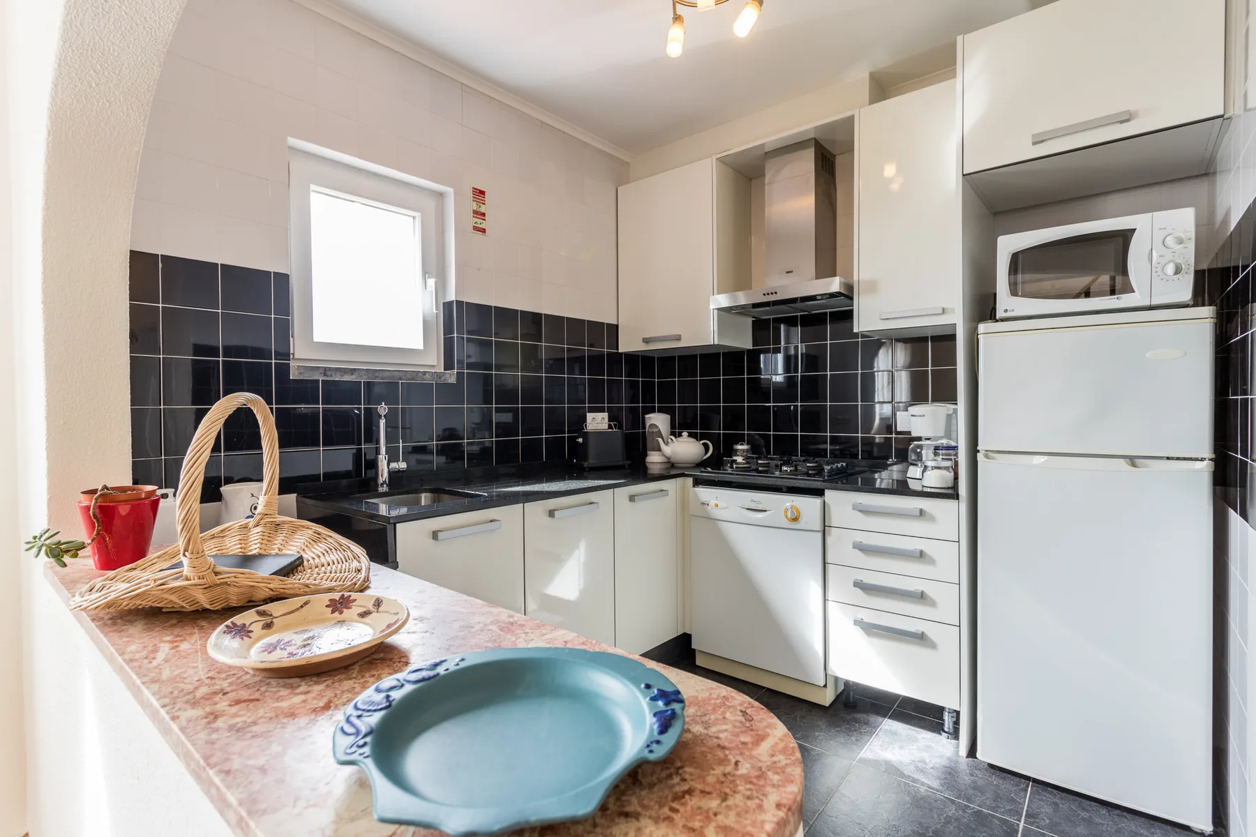 A kitchen with black tile backsplash, white cabinets, and a countertop.