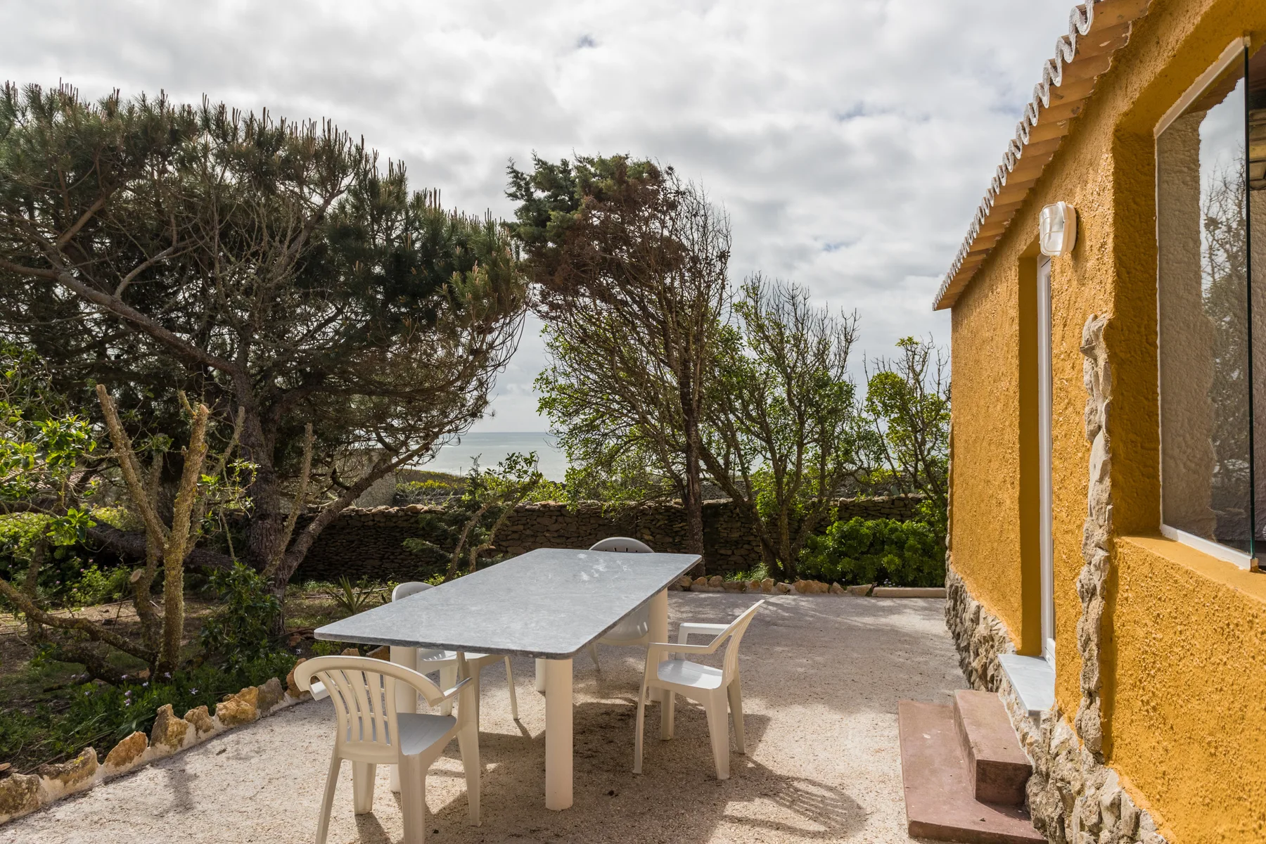 An outdoor patio with a table and seating beside a yellow house.