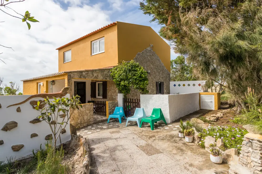 An exterior view of a house with a stone lower façade and outdoor seating.