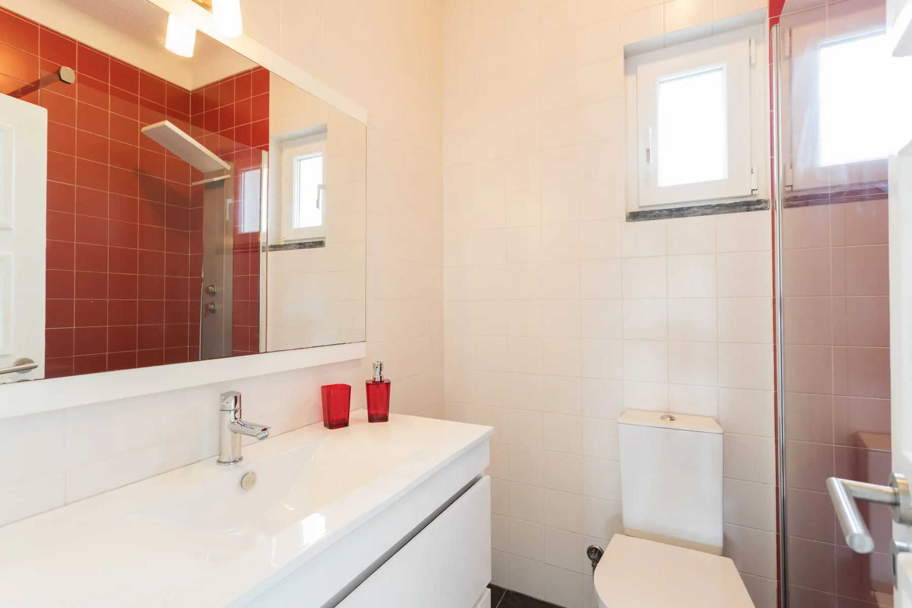 A tiled bathroom with a sink, toilet, and glass shower.
