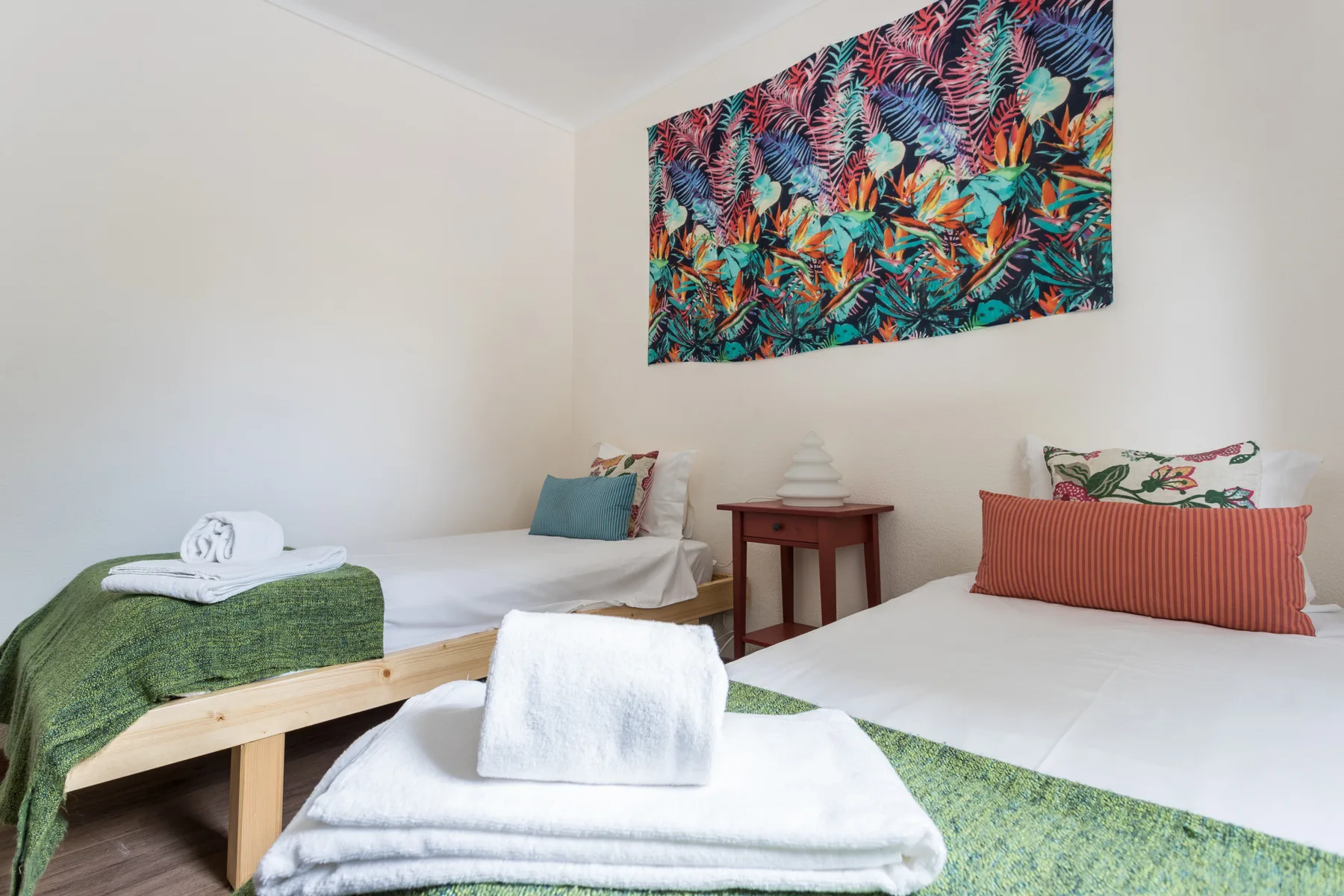 Un dormitorio con dos camas y arte botánico colorido en la pared.