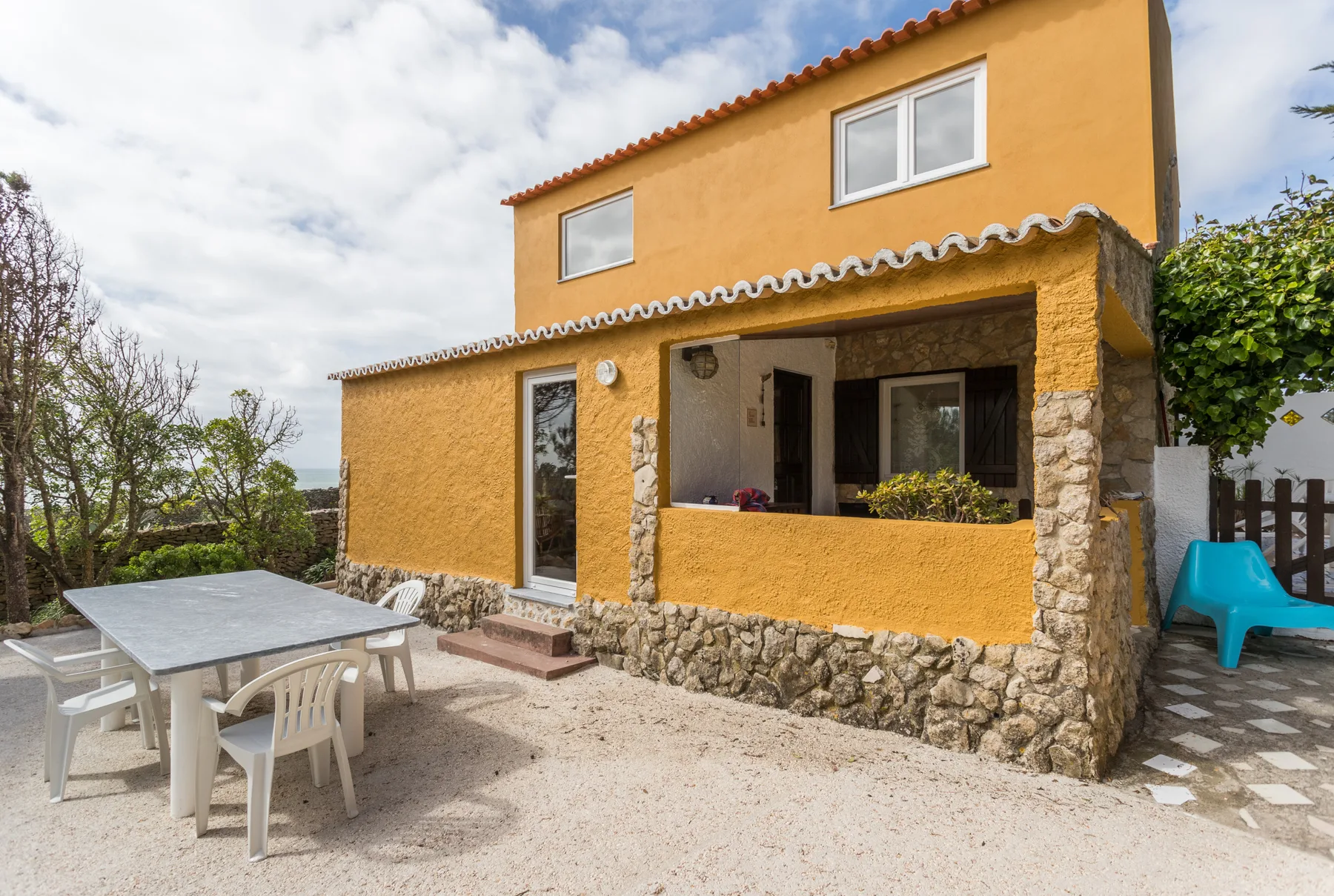 A yellow house with a covered patio and outdoor dining table.
