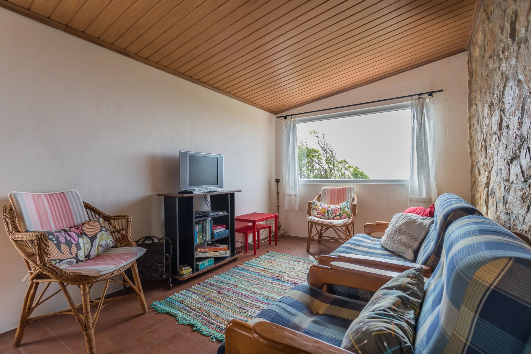 A living room with seating, a television, and a large window.