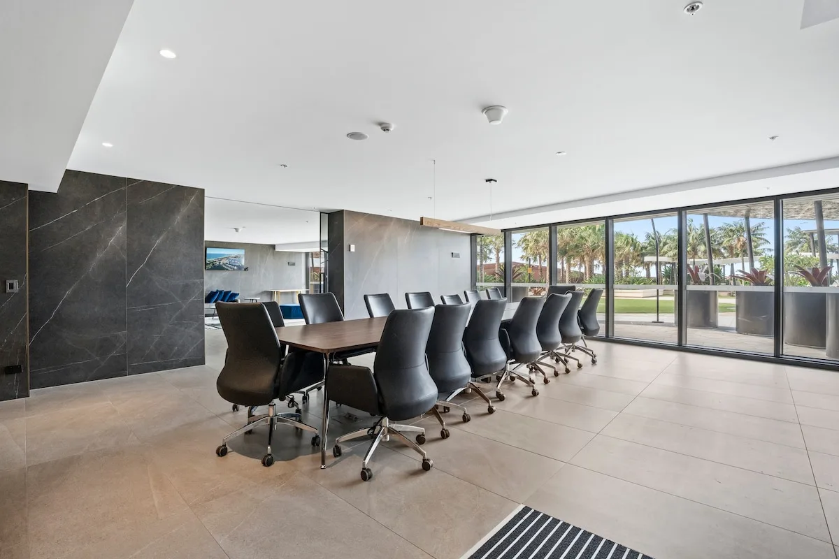 Una sala de reuniones con una mesa larga y asientos junto a ventanas de piso a techo.
