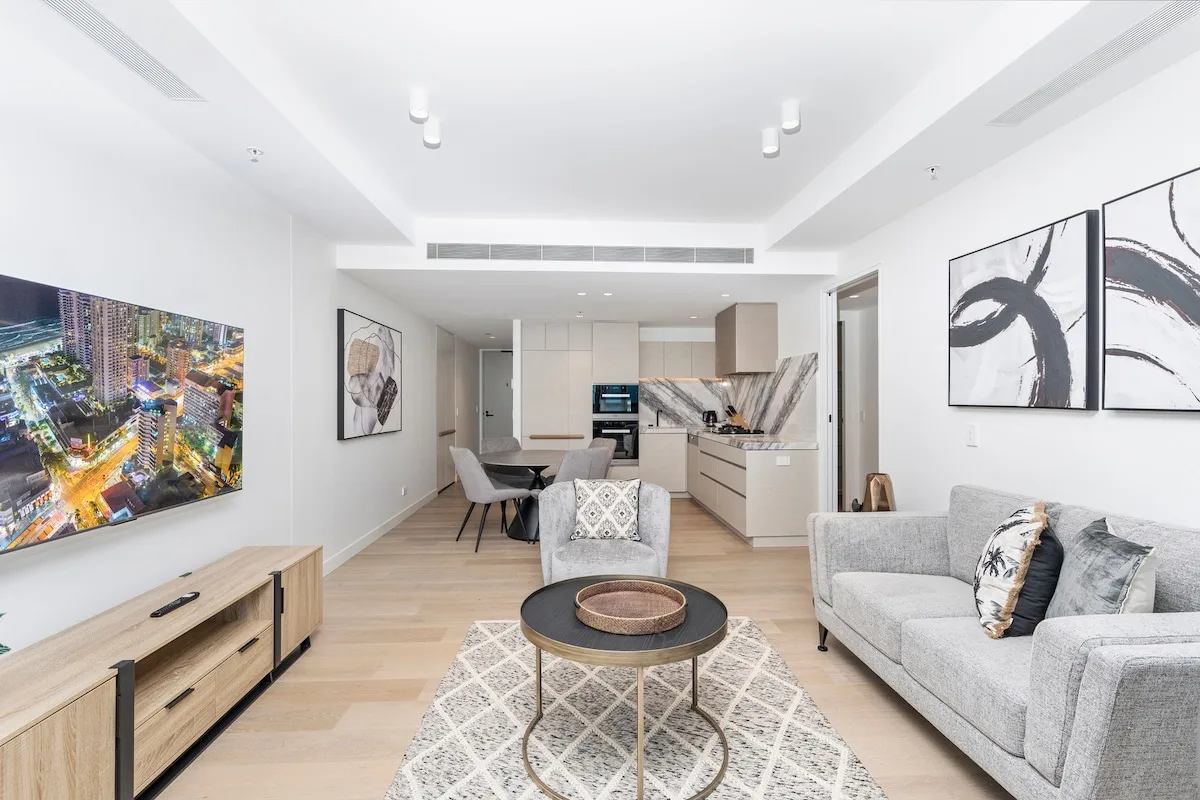 Una sala luminosa con asientos, una mesa de centro y una cocina abierta.
