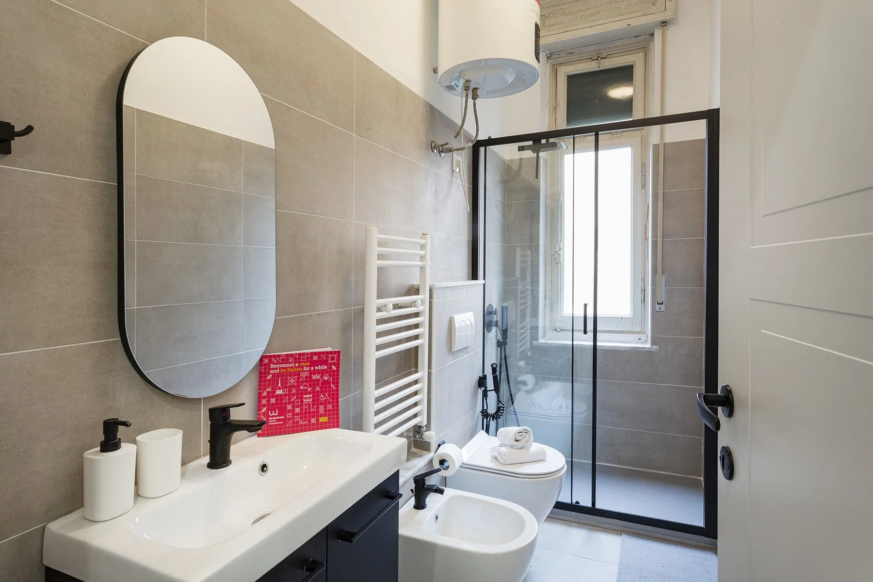 Un baño alicatado con lavabo, espejo, inodoro y ducha de vidrio.