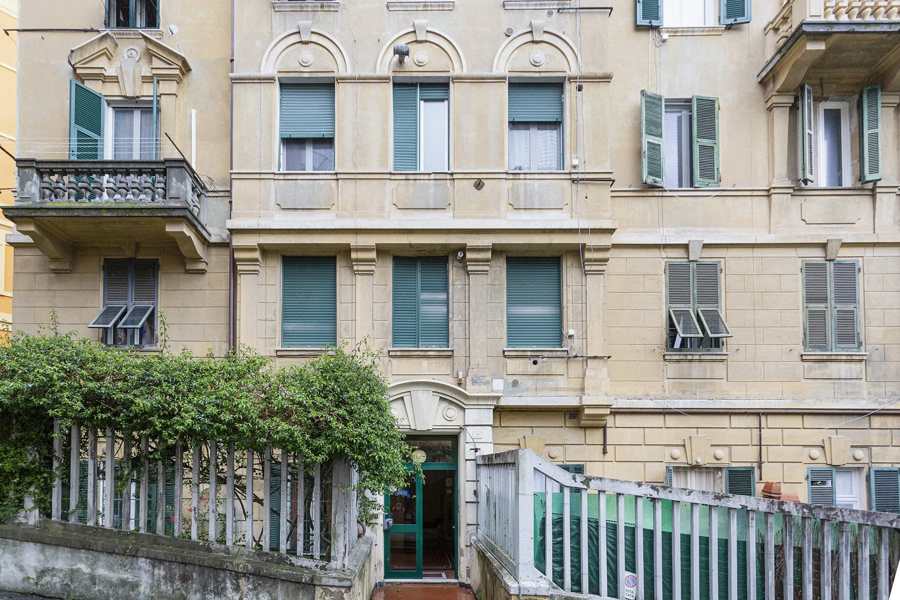 Fachada de un edificio beige con ventanas con persianas y balcones.