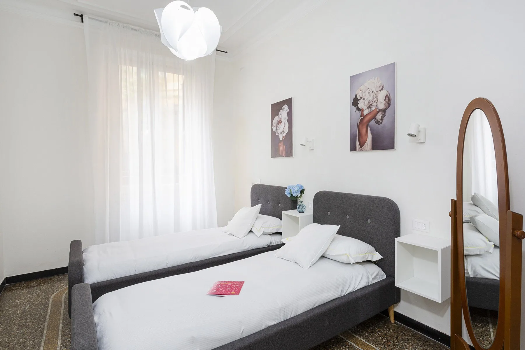 Un dormitorio luminoso con dos camas, ropa de cama blanca y cuadros.