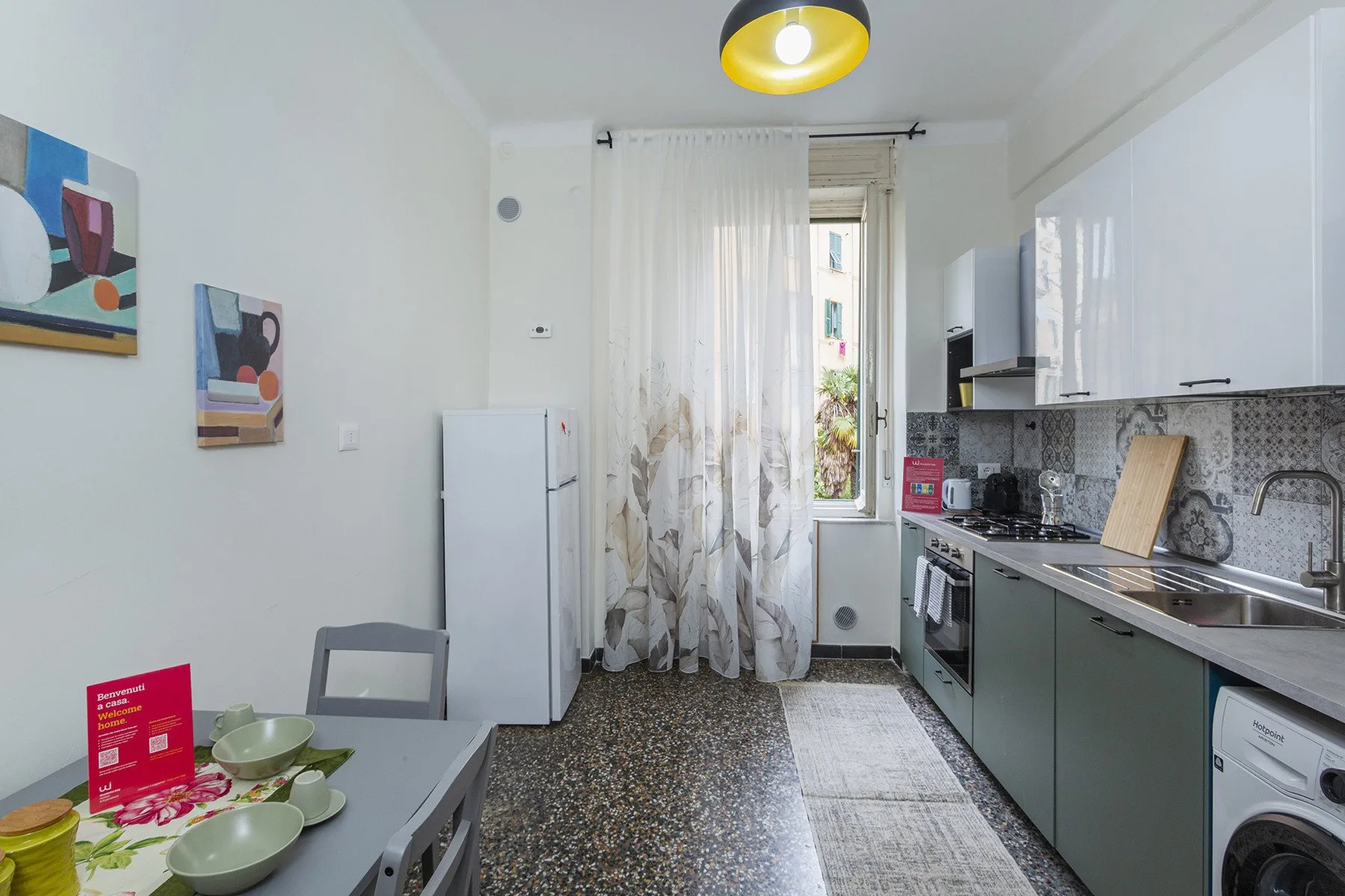 Una cocina luminosa con mesa de comedor, gabinetes blancos y una ventana.