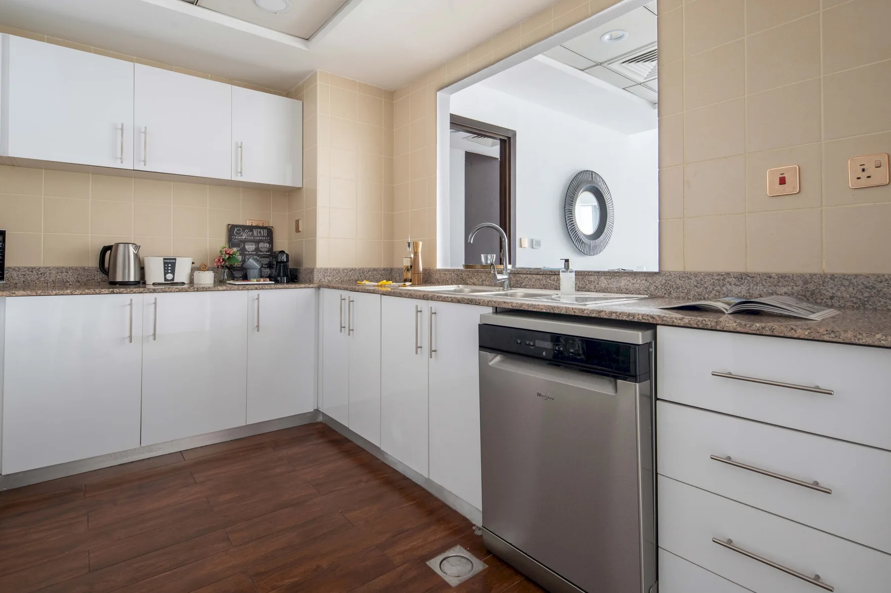 A modern kitchen with white cabinets, a countertop, and a dishwasher.