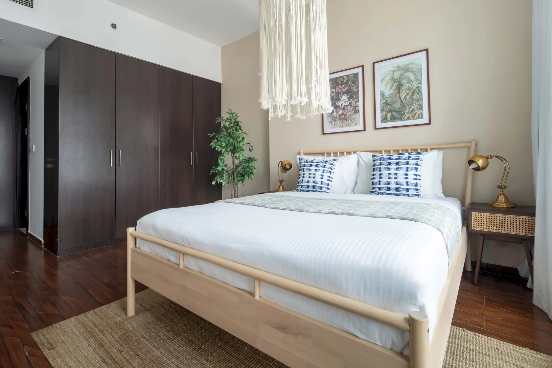 A bedroom with a light wood bed, white bedding, and dark wardrobes.