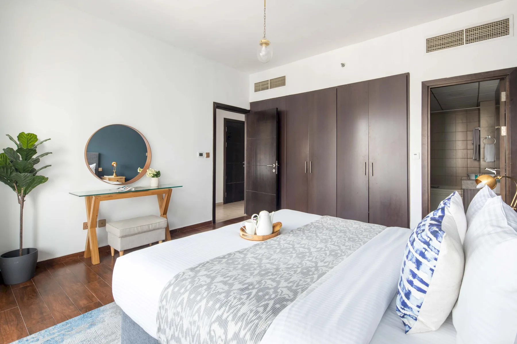A bedroom with a large bed, dark wardrobes, and a small dressing table.