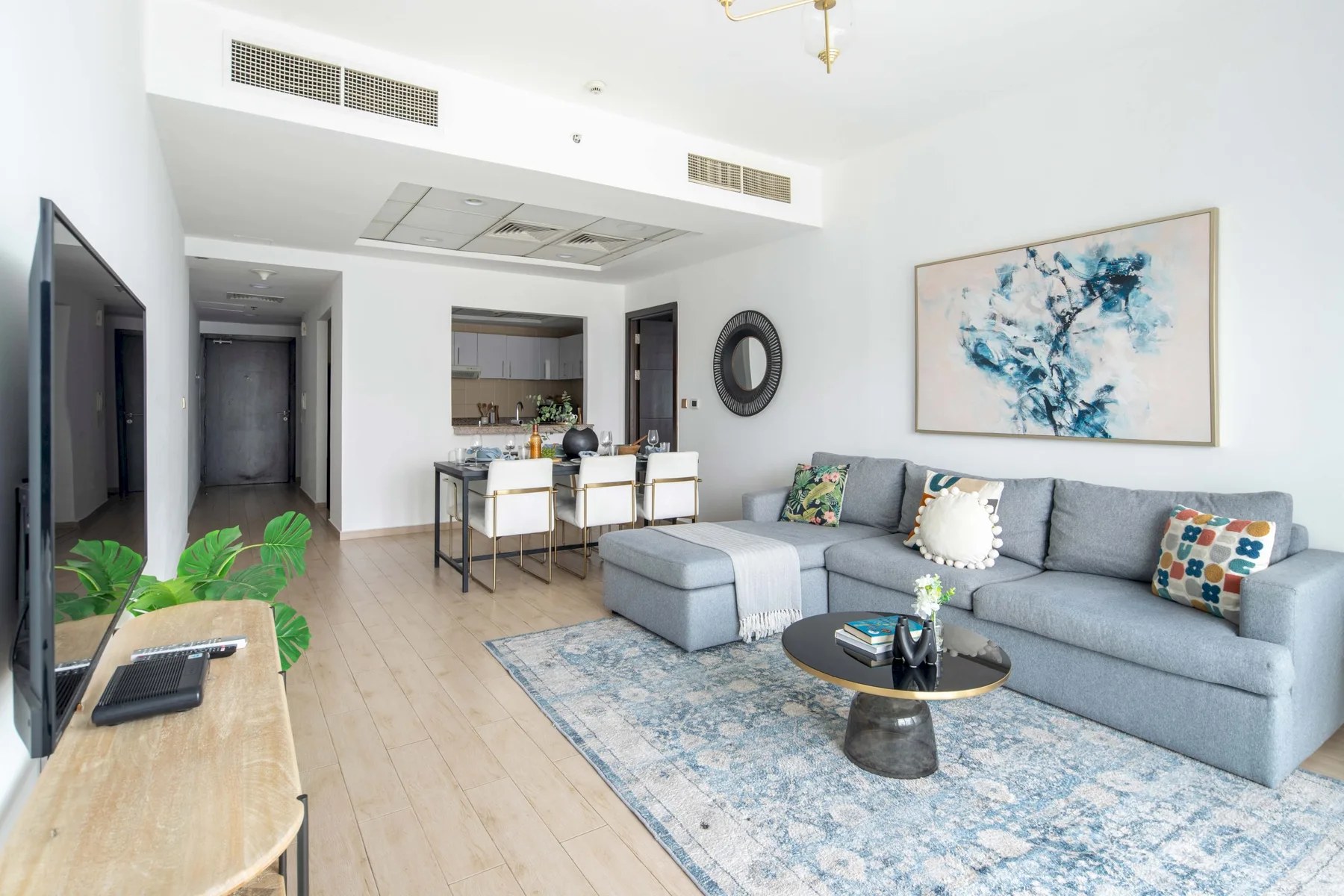 A bright living room with a gray sectional sofa and a dining area.