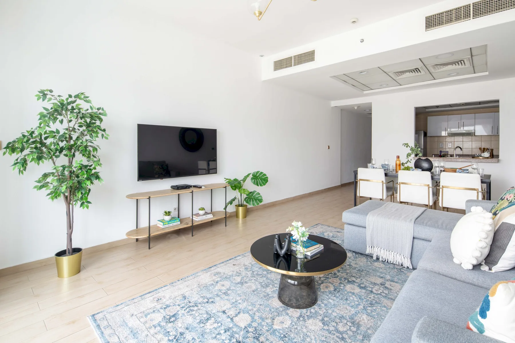 A bright living room with seating, a television, and a dining area.