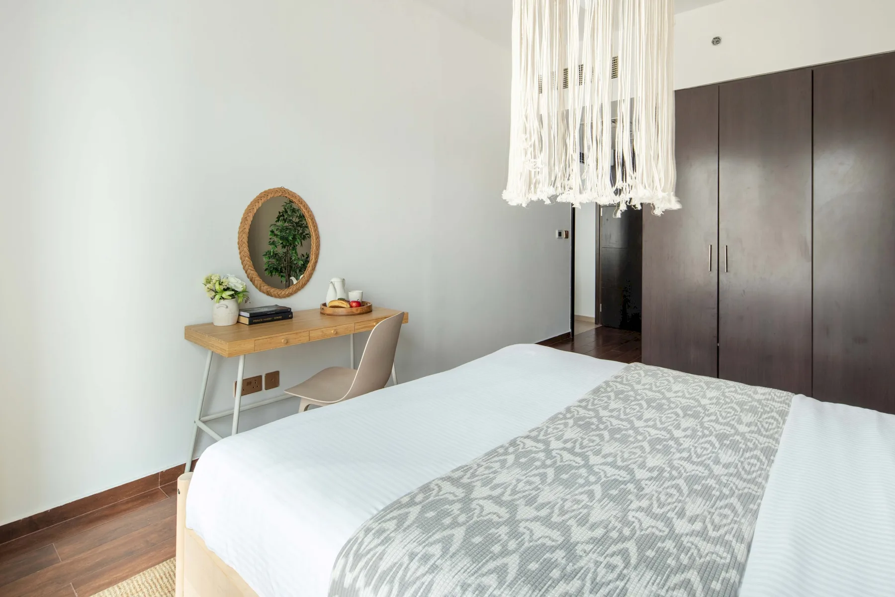 A bedroom with a bed, a desk, and a large wardrobe.