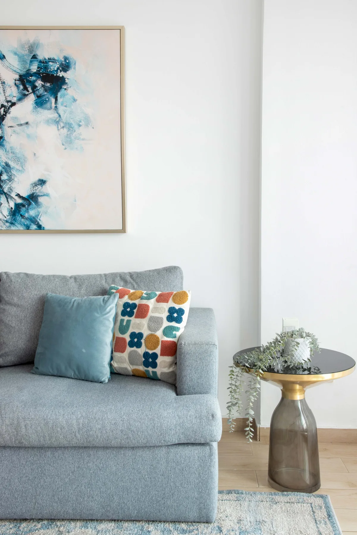 A living room with gray seating, colorful cushions, and framed abstract artwork.