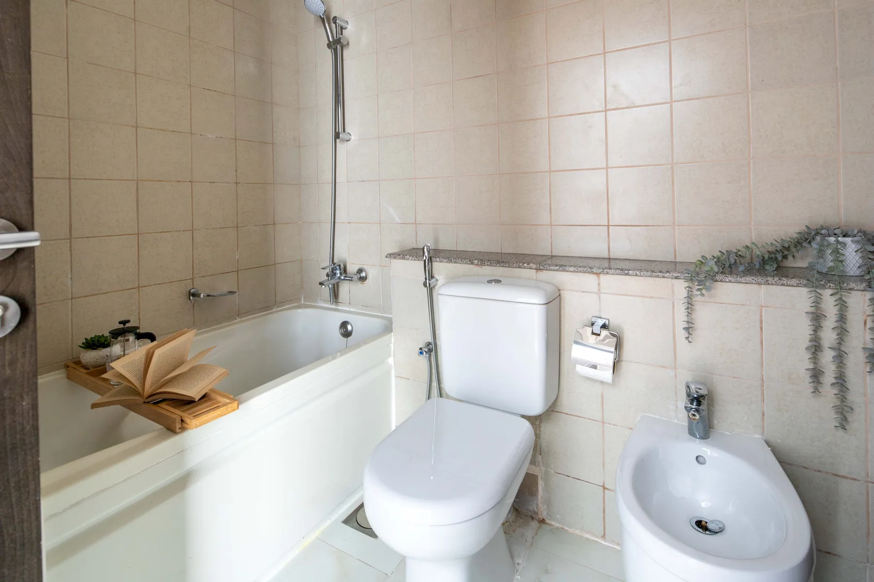 A tiled bathroom with a bathtub, shower, toilet, and bidet.
