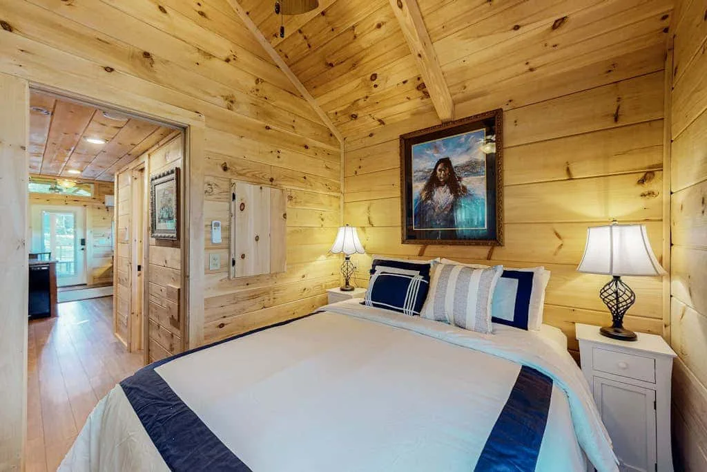 Un dormitorio con una cama bien tendida y paredes revestidas de madera.