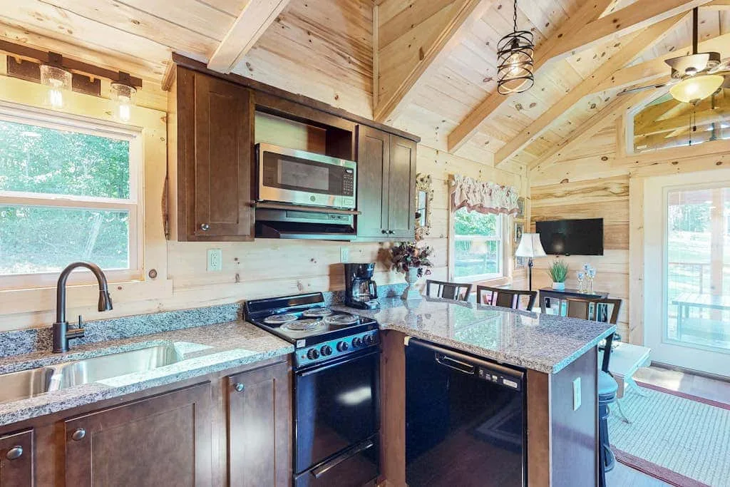 Una cocina revestida de madera con una isla central y ventanas grandes.
