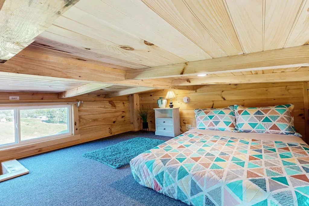 Un dormitorio de techo bajo con una cama y ropa de cama geométrica y colorida.