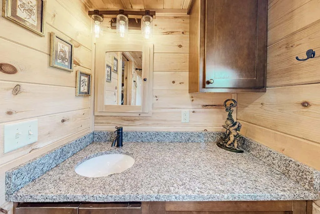 Un tocador de baño con encimera moteada, lavabo, espejo y armario de pared.