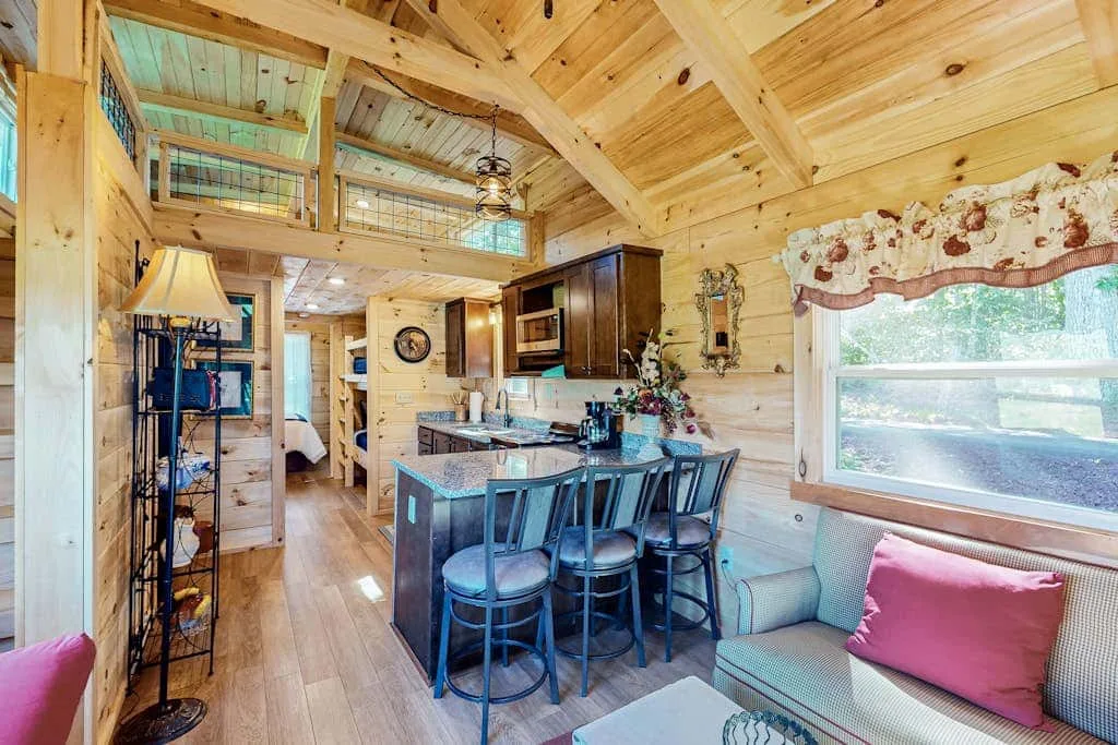 A wood-paneled open-plan living and dining area with a kitchen island and seating.