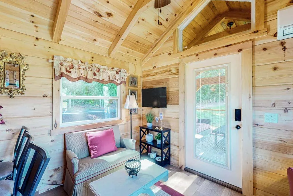 A wood-paneled sitting room with a sofa, television, and glass door.