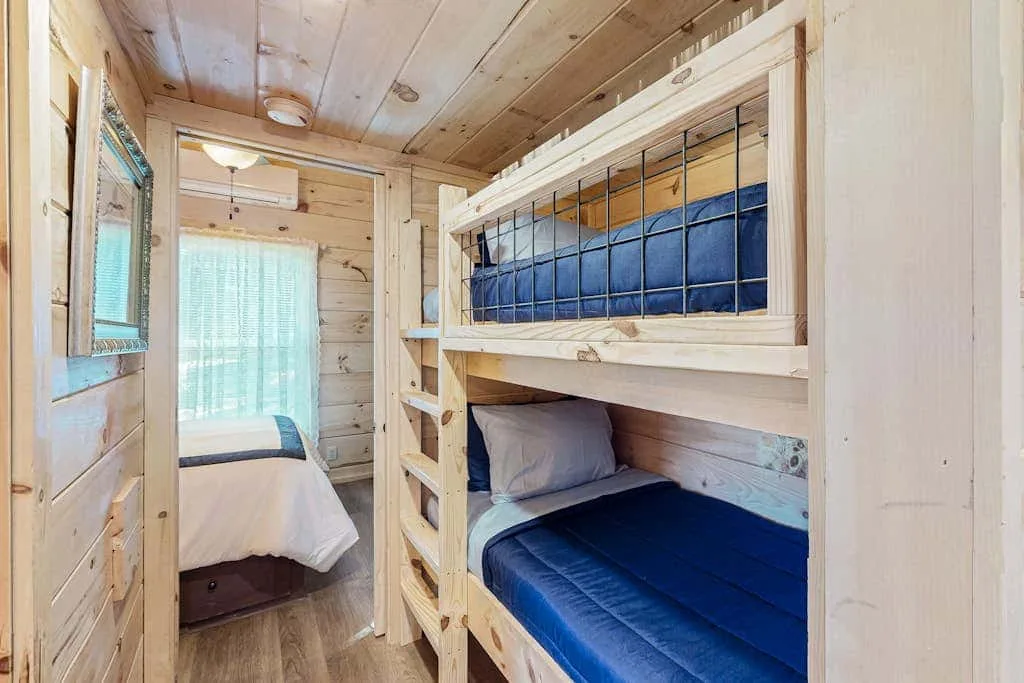Un dormitorio compacto con literas de madera y una ventana con cortinas.