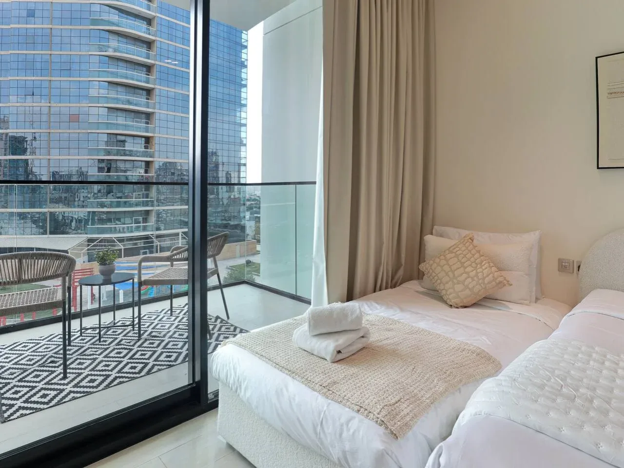 A bedroom with a neatly made bed beside a glass balcony door.