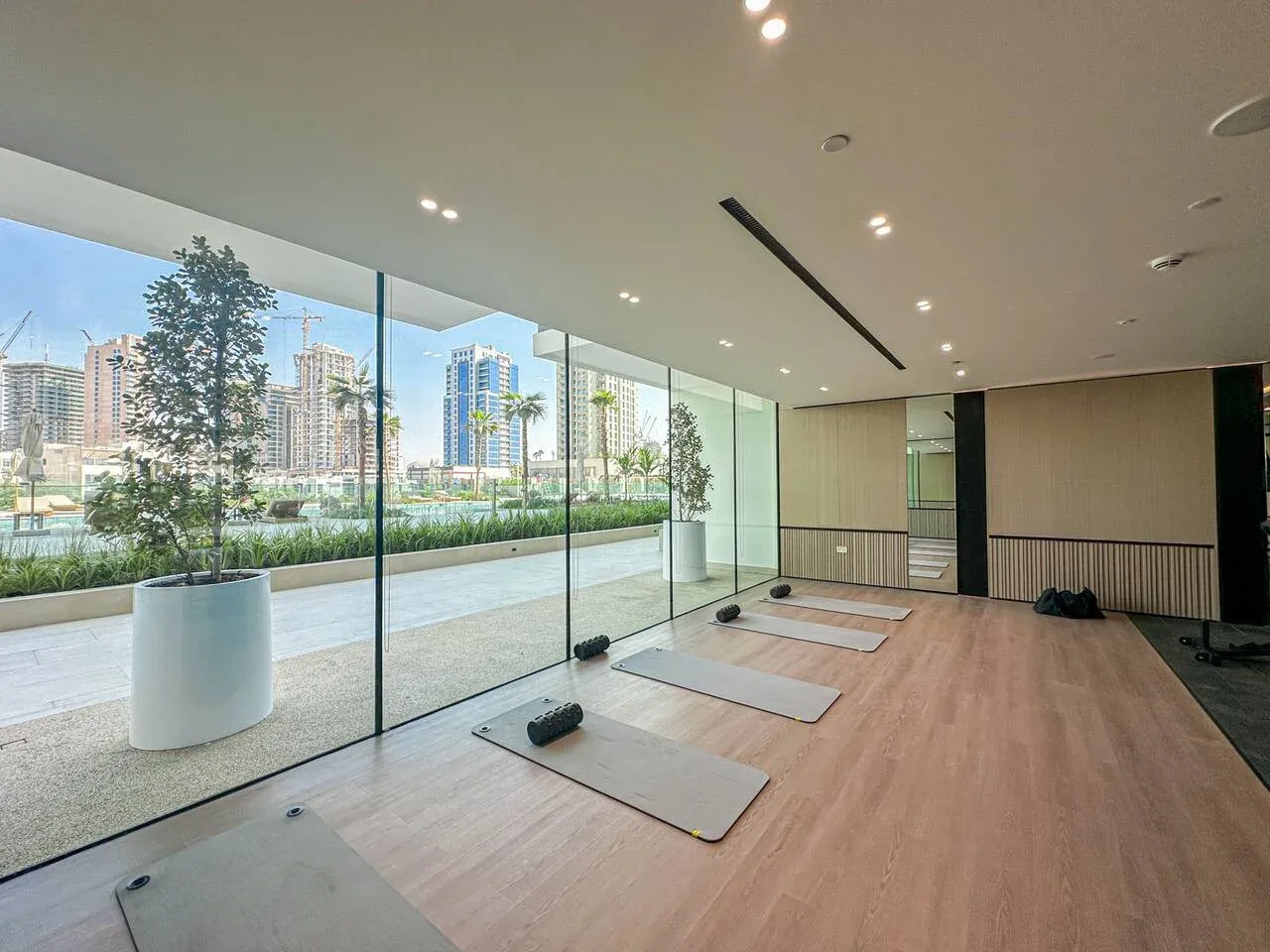 A spacious exercise studio has floor mats beside floor-to-ceiling windows overlooking the city.