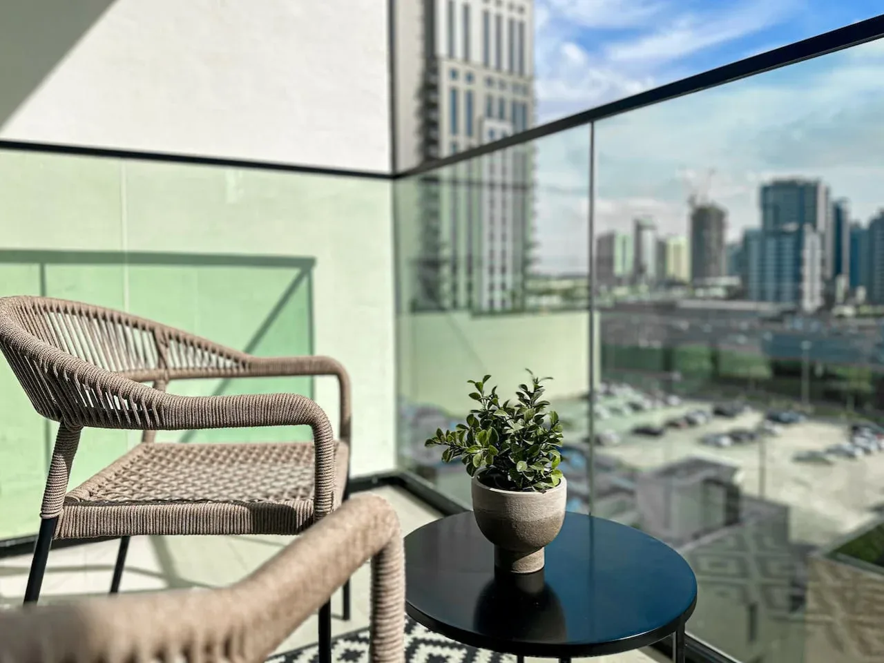 A balcony seating area with a small potted plant beside glass railings.
