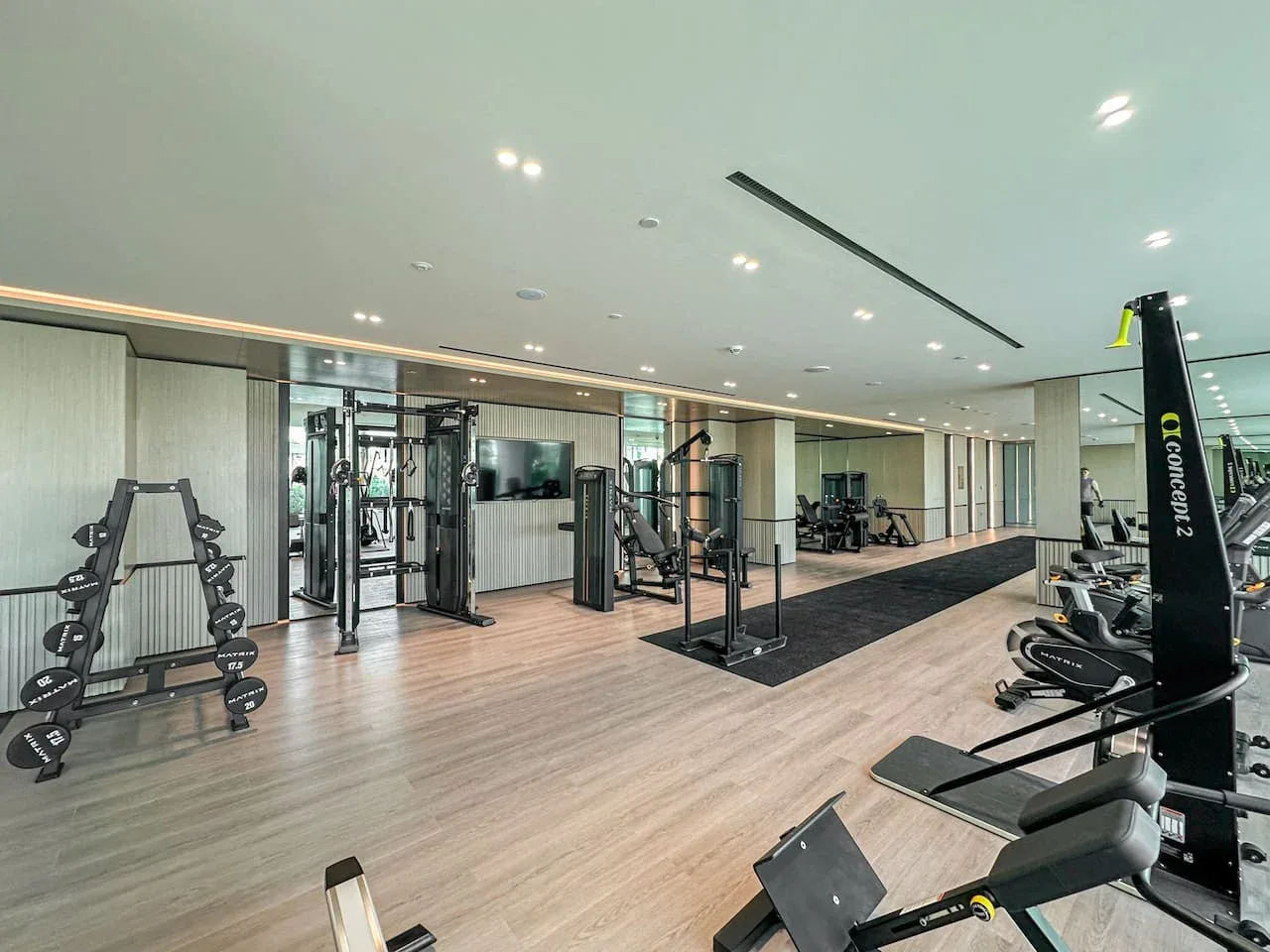 A gym with exercise machines, weights, and a mirrored wall.