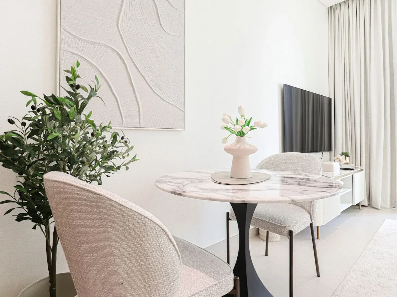 A bright living area with a round table, seating, and a television.