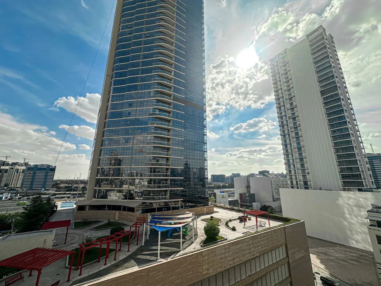 Two modern high-rise buildings stand beneath a partly cloudy sky.