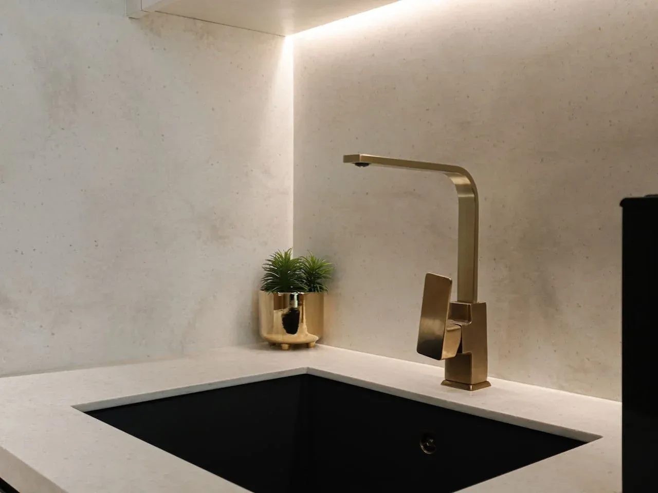 A modern bathroom vanity with a dark rectangular sink and a tall faucet.