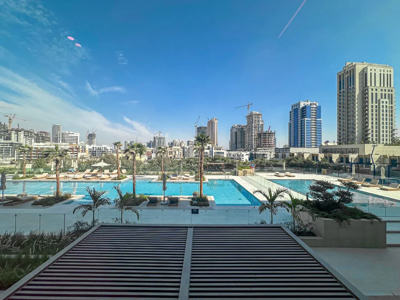 A rooftop pool area overlooks a city skyline under a clear blue sky.