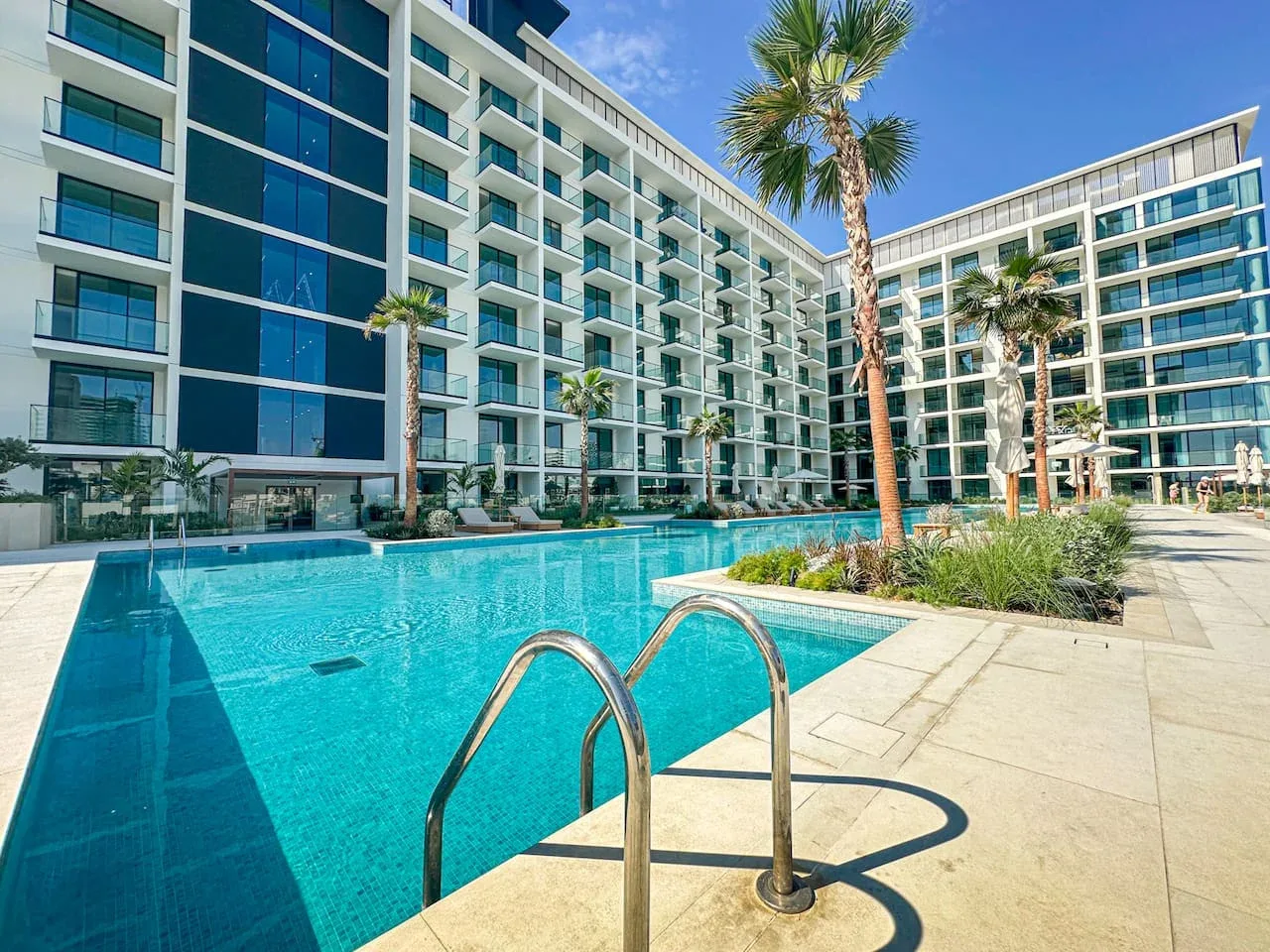 A swimming pool sits in a courtyard surrounded by a modern multi-story building.
