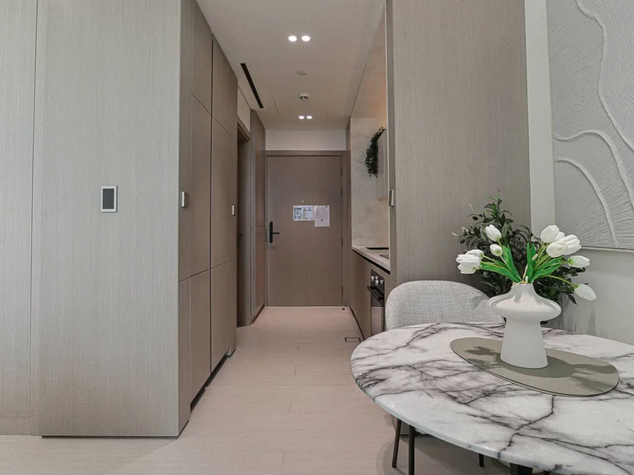 A modern room with a marble dining table and a hallway in the background.