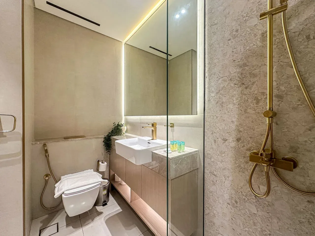 A modern bathroom with a vanity, toilet, and glass shower partition.