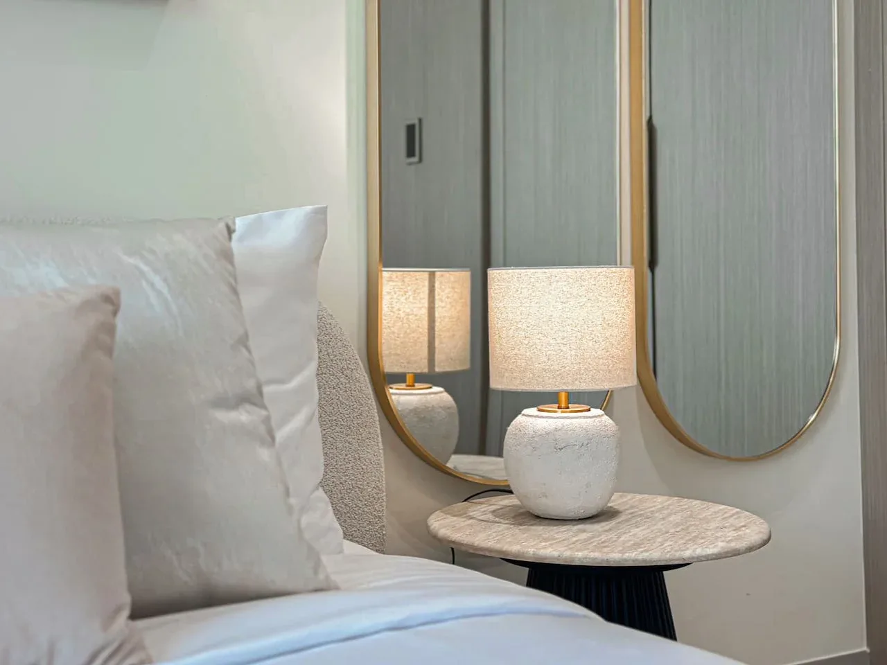 A bedroom seating area with a bed beside a small table and lamp.