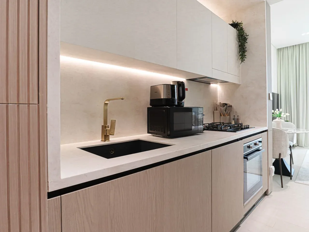 A modern kitchen with a black sink, countertop appliances, and a cooktop.