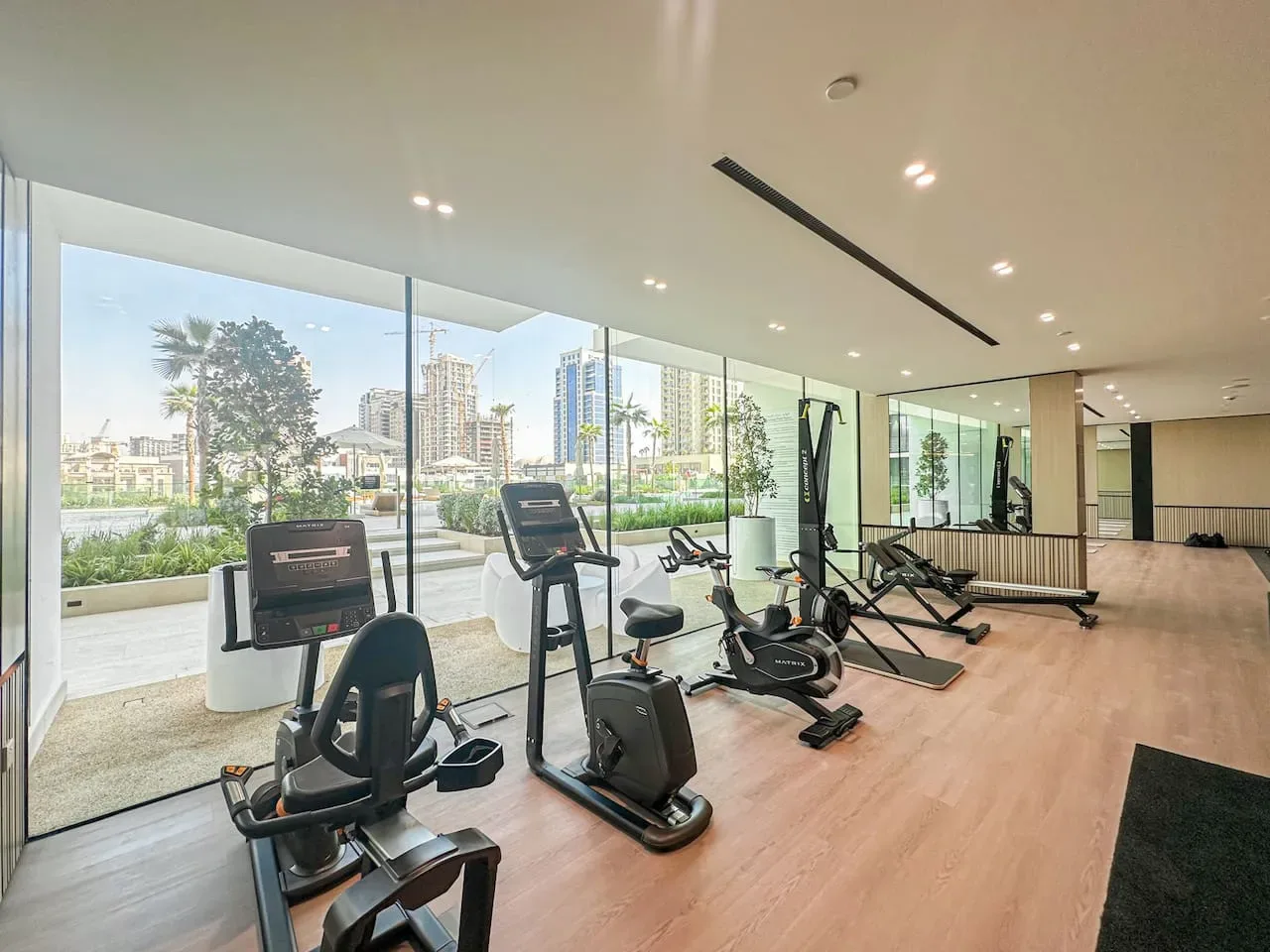 A bright gym with exercise equipment beside large windows.
