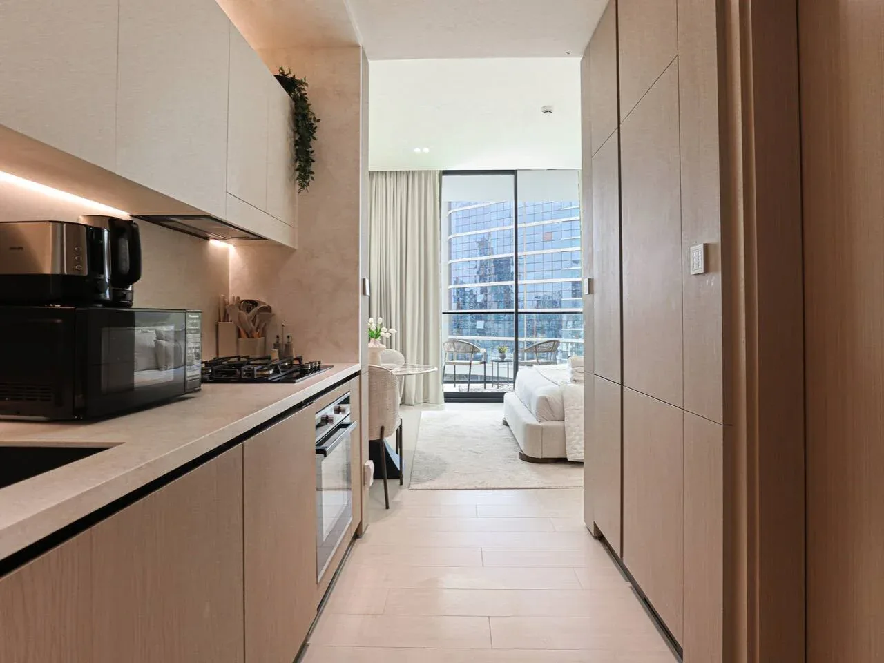 A compact kitchen opens into a bright living area with large windows.