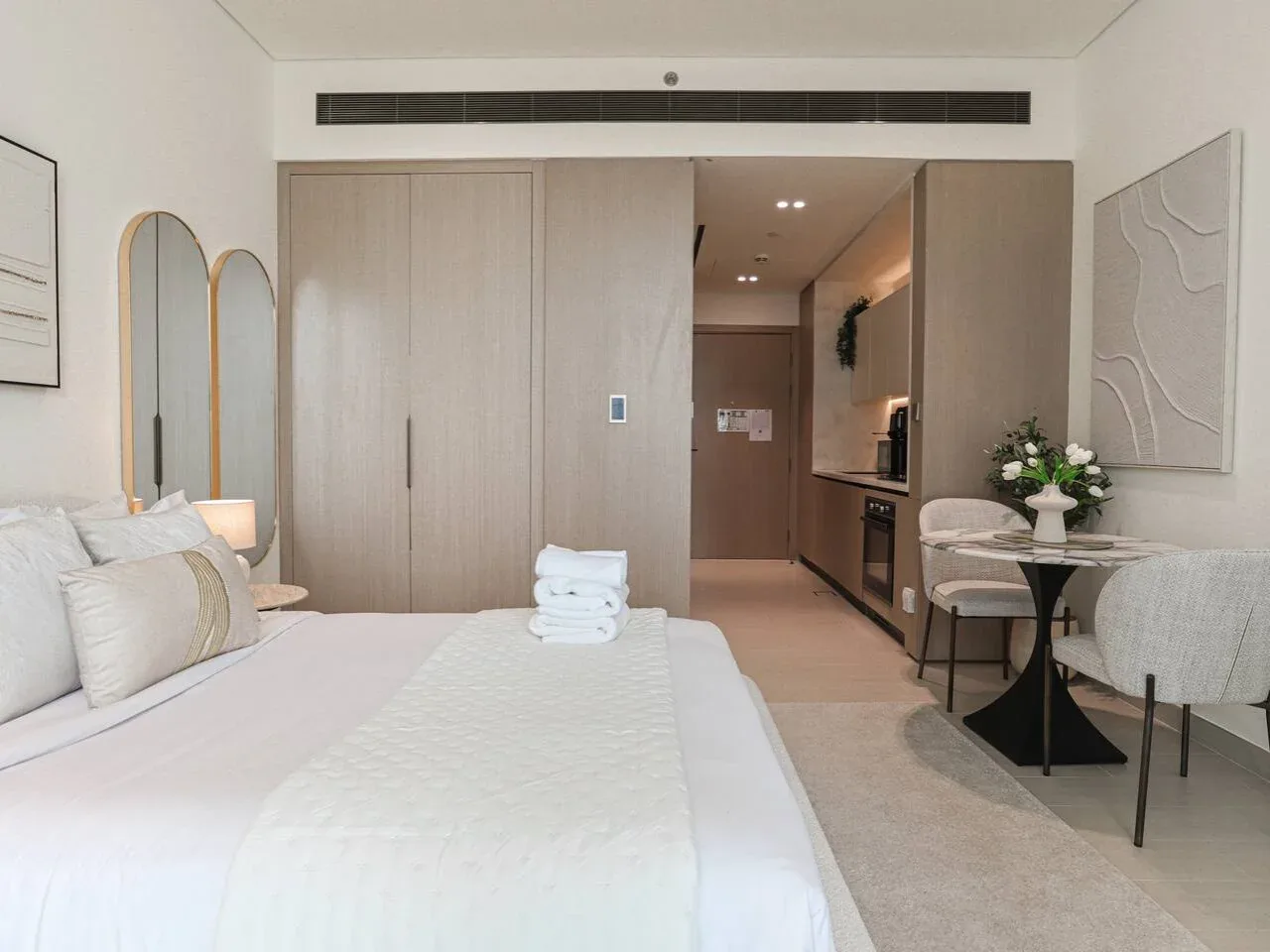 A bright bedroom with a neatly made bed and a small seating area.