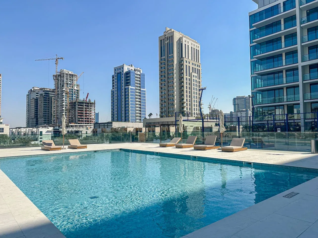 A rooftop swimming pool overlooks a cluster of high-rise buildings.
