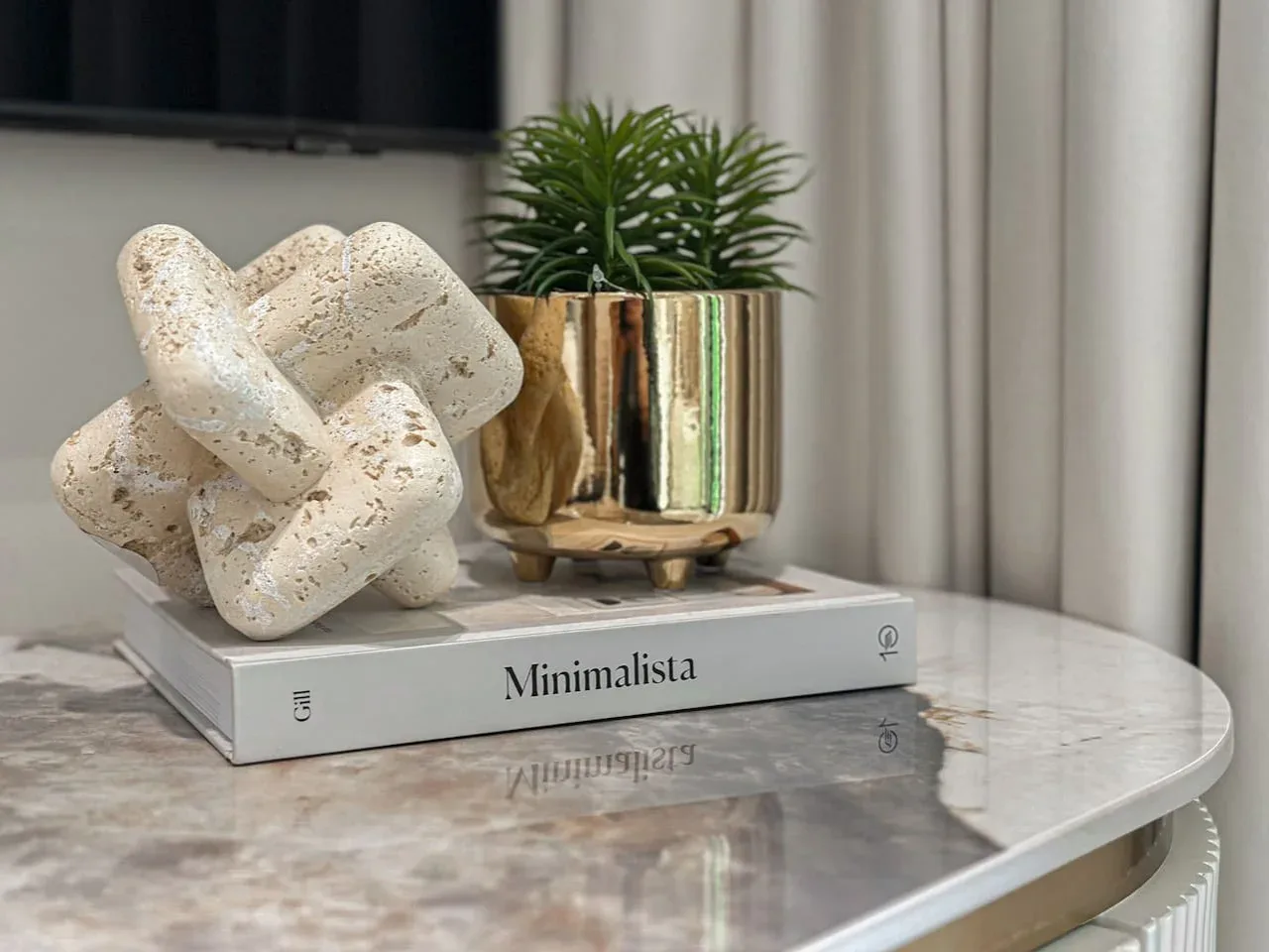 A marble-topped side table displays a sculptural ornament and a potted plant.