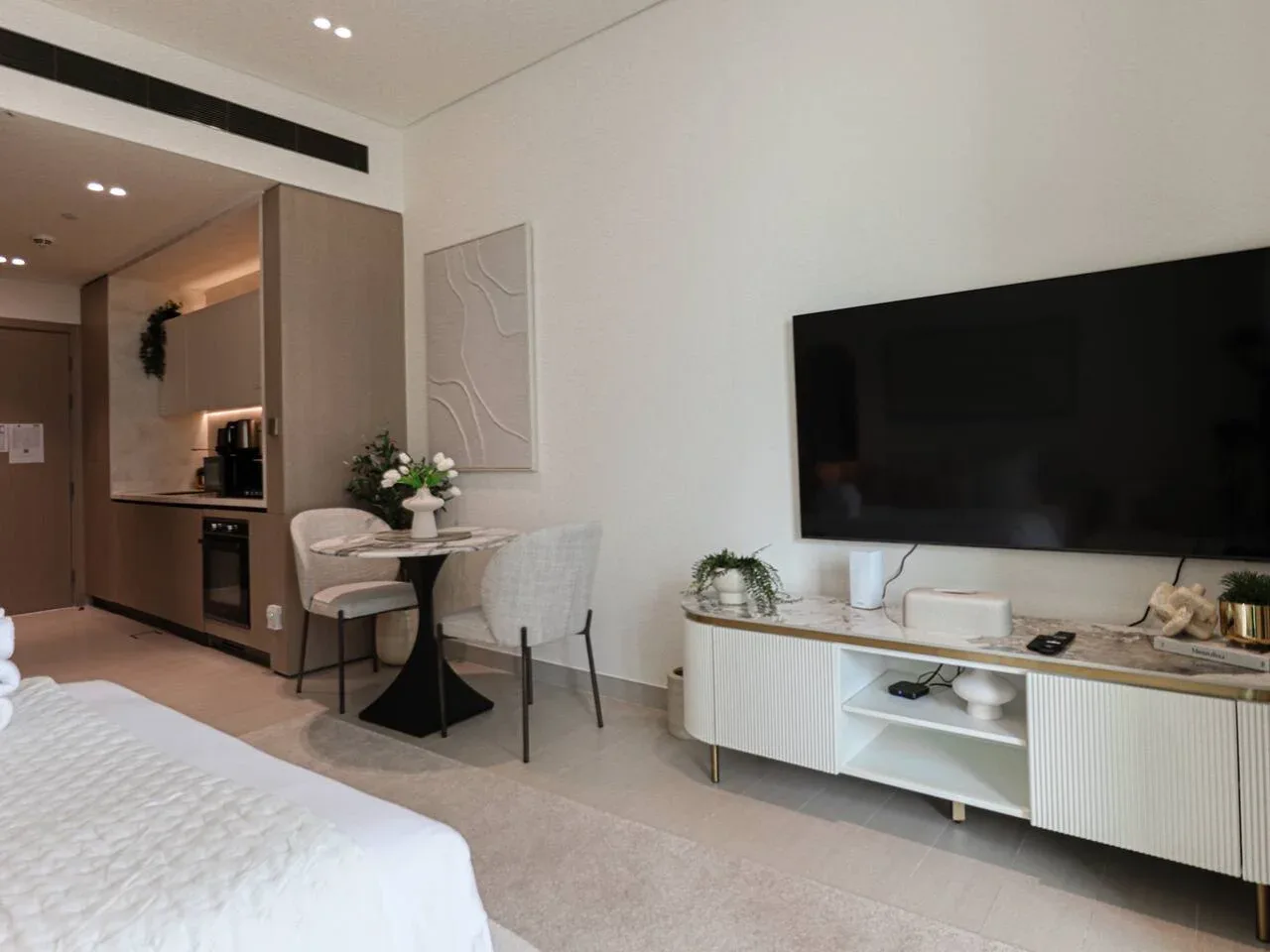 A bedroom with a bed, a television, and a small dining area.