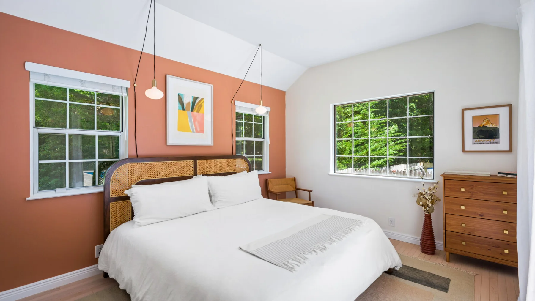 Un dormitorio con una cama grande, ventanas y una cómoda.