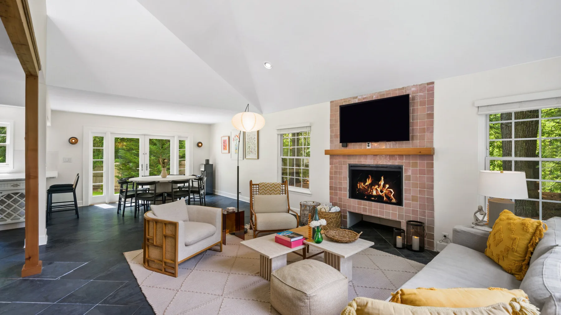Una sala luminosa con chimenea y un comedor junto a las ventanas.